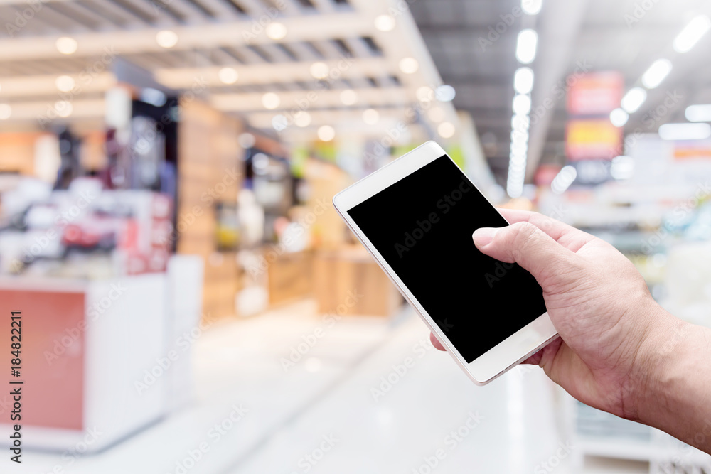 带模糊背景的人手智能手机购物中心或百货公司的背景图像，带有散焦和p