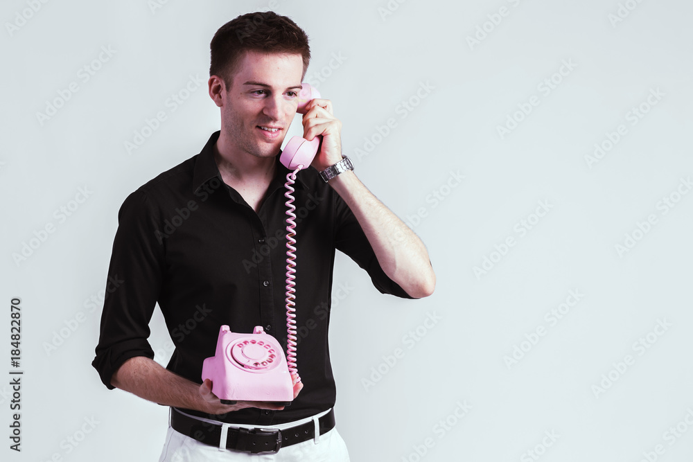 一个年轻人在白色背景下用老式电话交谈的肖像