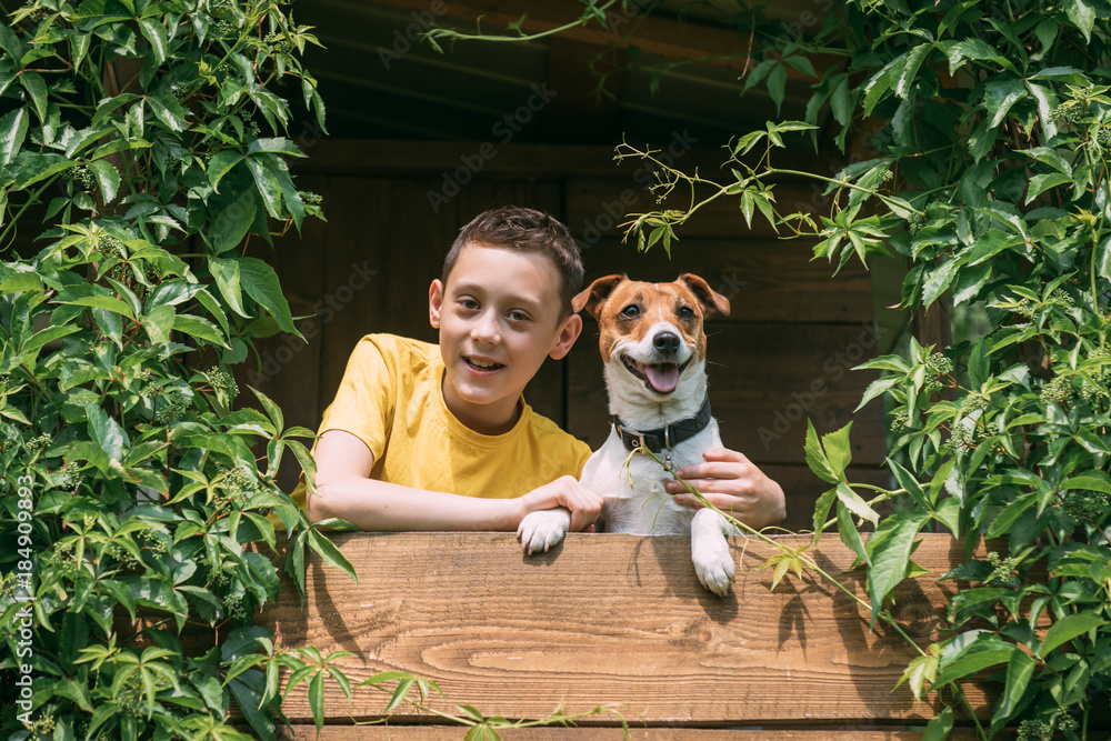 微笑的男孩和狗在树屋上。夏天！童年概念