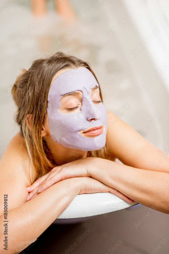 一个戴着面膜的女人躺在浴室复古浴缸里的肖像