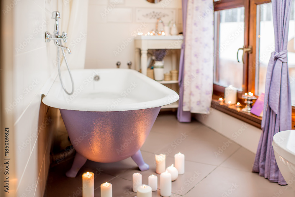 美丽的浴室内部，复古的紫罗兰色浴缸，装饰着蜡烛