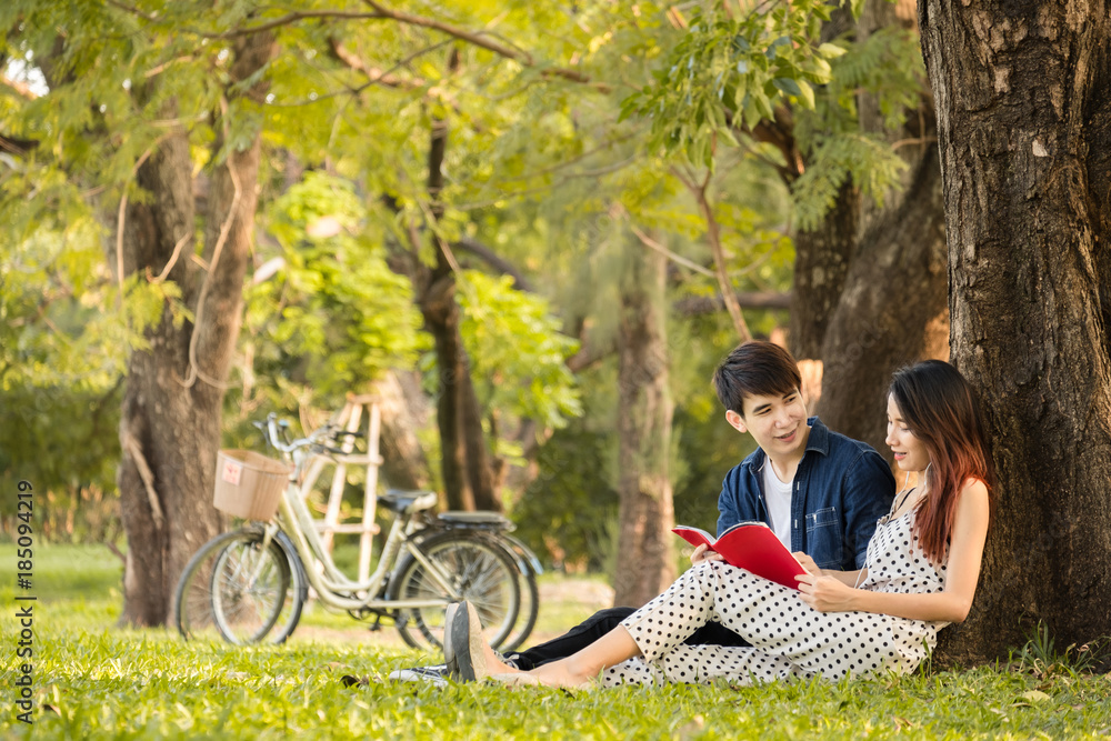 亚洲情侣在公园户外的生活方式，看书听音乐，放松和快乐