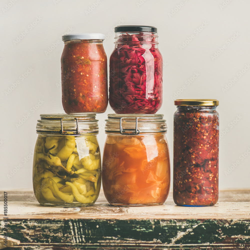 秋季时令腌制或发酵的彩色蔬菜，装在老式厨房抽屉上的玻璃罐里。