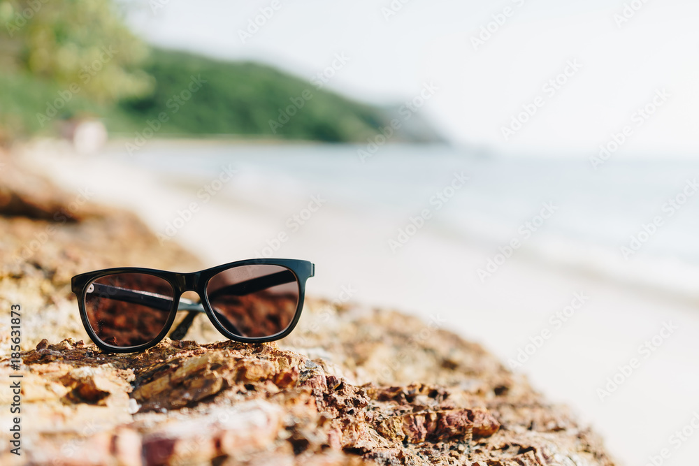 在假期阳光明媚的日子里，在海滩上的岩石上放了一个太阳玻璃。