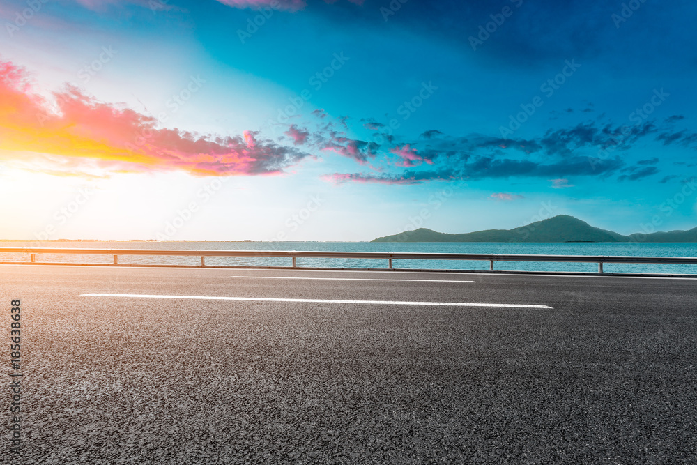 空旷的柏油公路和日落时的蓝海自然景观