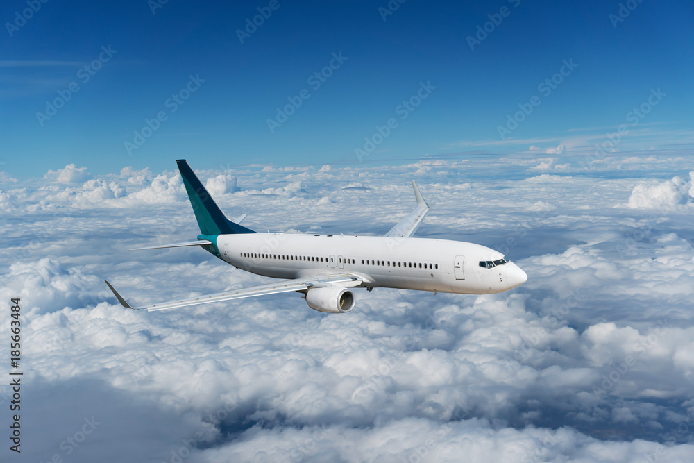 Commercial airplane flying above clouds and clear blue sky over beautiful scenery nature background,