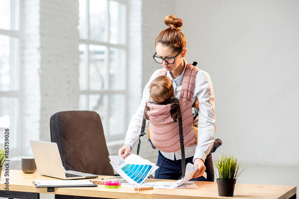 疲惫的女商人带着她的小儿子在办公室处理纸质文件