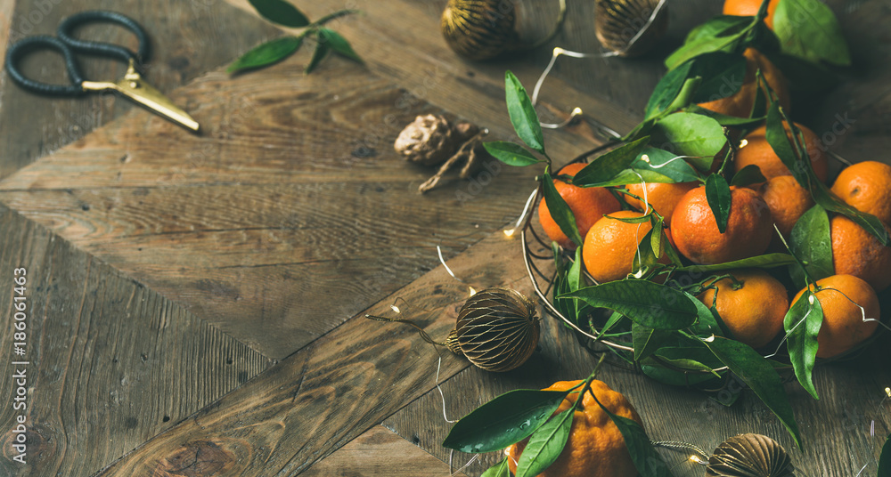 圣诞或新年餐桌。托盘里有新鲜成熟的橘子和叶子，装饰玩具，剪刀和