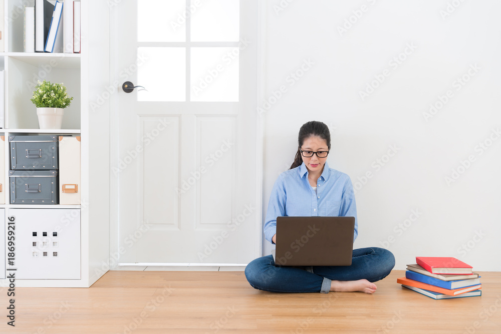 女导师坐在地板上用移动笔记本电脑