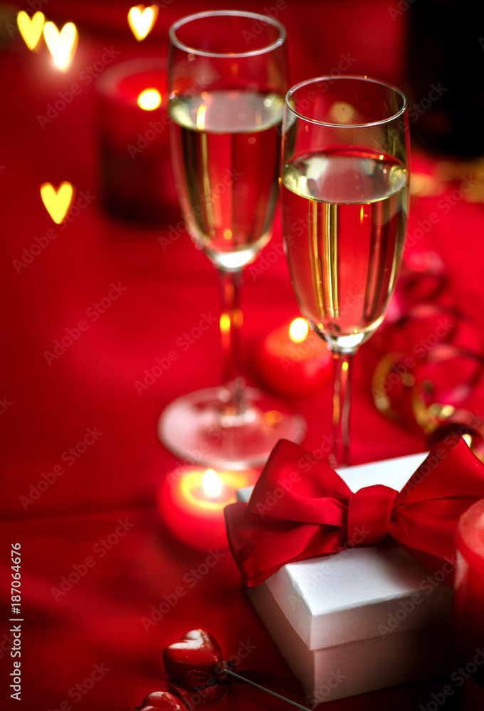 Valentines Day romantic dinner. Date. Champagne, candles and gift box over holiday red background