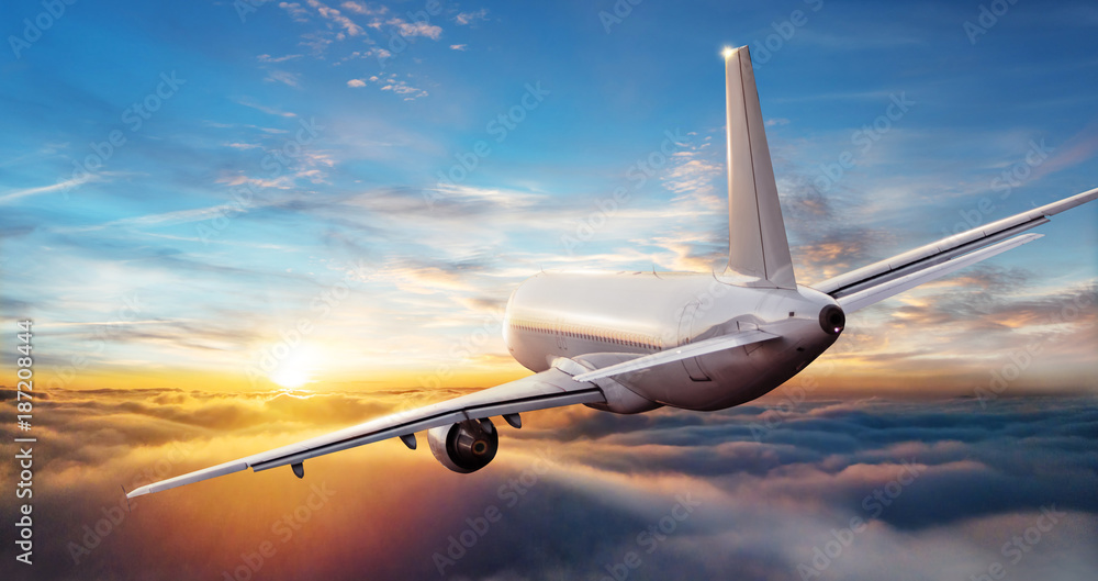 商业飞机喷气式客机在美丽的日落光线下在云层上方飞行。