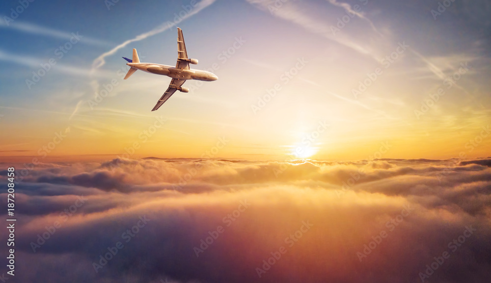 商业飞机喷气式客机在美丽的日落中在云层上方飞行。