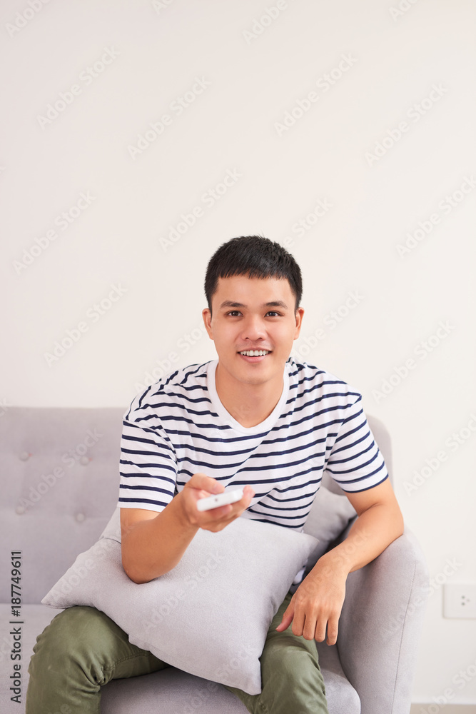 年轻英俊的男人坐在沙发上在家看电视