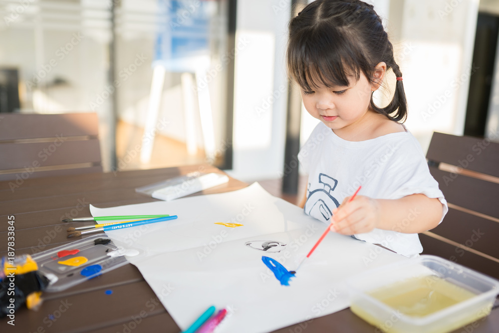 亚洲小女孩用画笔和五颜六色的颜料作画