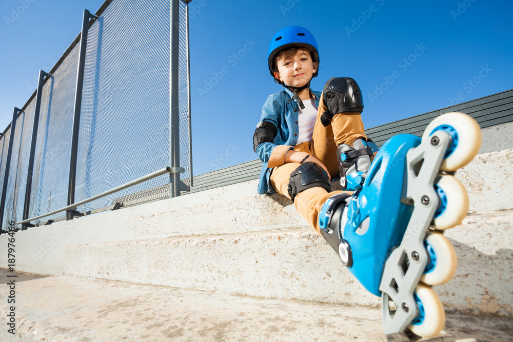 滚轴男孩在滑冰公园的台阶上休息