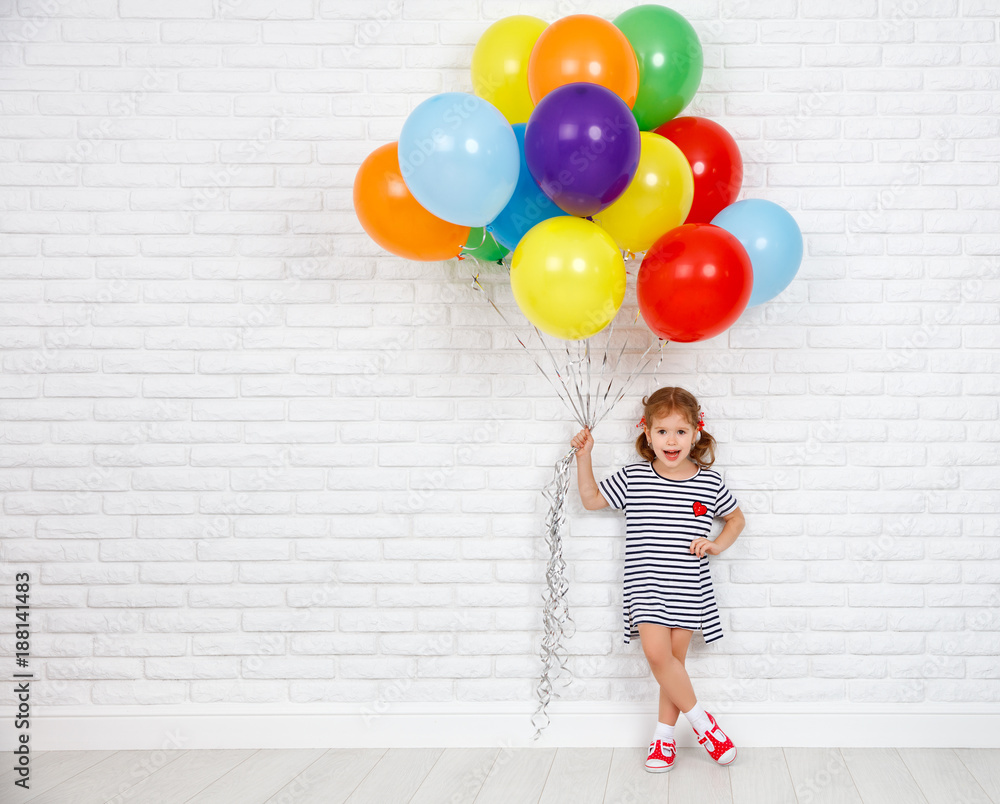 砖墙附近有彩色气球的快乐有趣的小女孩