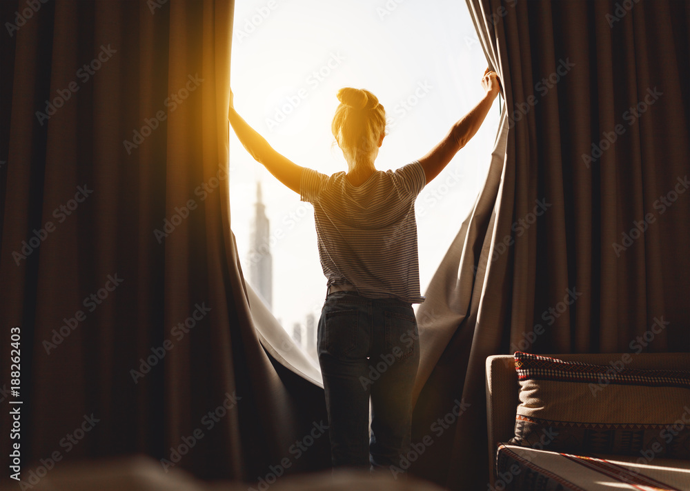 快乐的女人早上伸懒腰打开窗帘