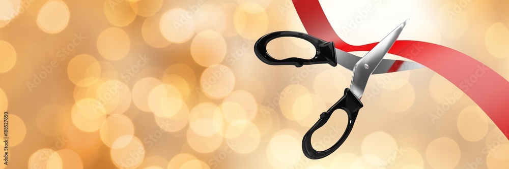 Scissors cutting ribbon with gold bokeh lights