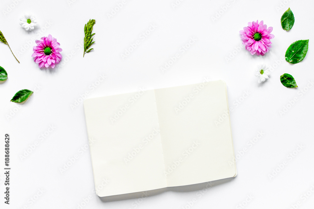 桌子背景上的花瓣和白色笔记本俯视图mo