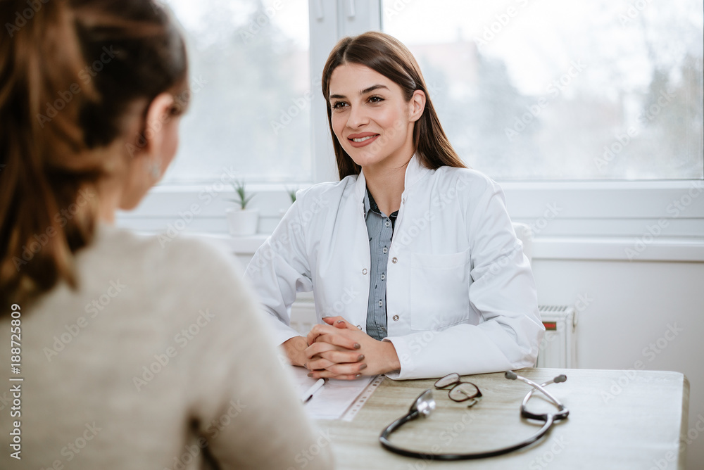 Beautiful female doctor in white medical coat is consulting her patient.