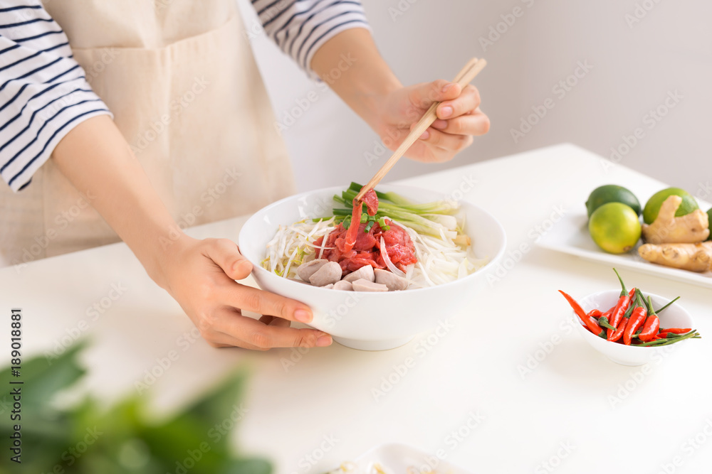 女厨师准备越南传统汤Pho bo，配香草、肉、米粉