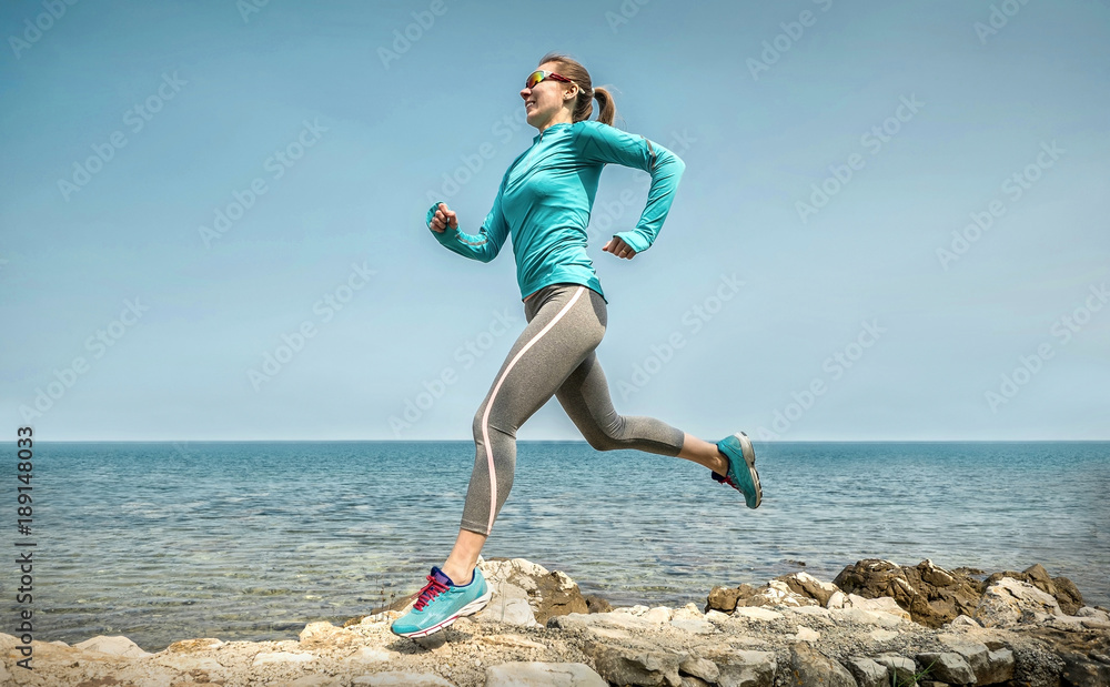 阳光明媚的苏，一个女人在阳光下沿着海岸奔跑