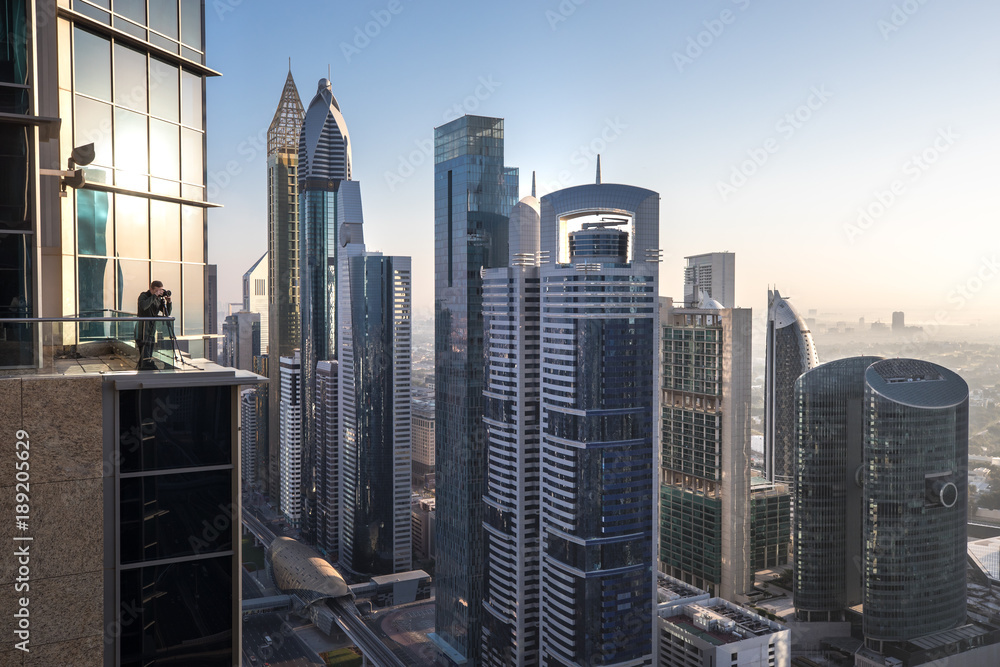 View of a photographer in Dubai International Financial District at sunrise as viewed from a rooftop