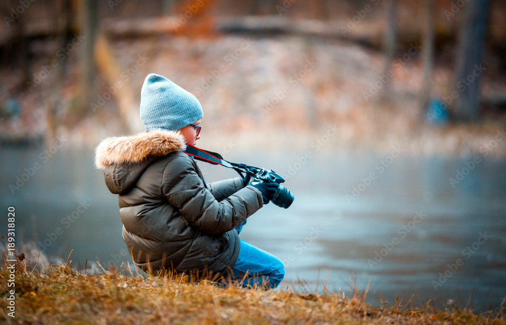 Boy using digital camera taking photo in the nature, hobby concept
