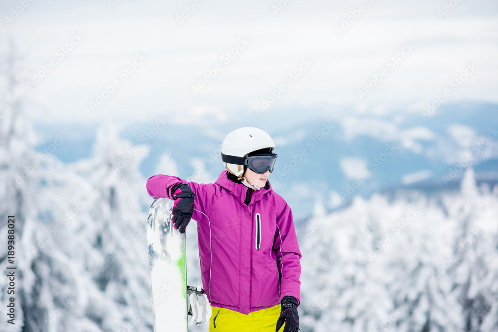 一位年轻的单板滑雪女子站在户外雪山上的肖像