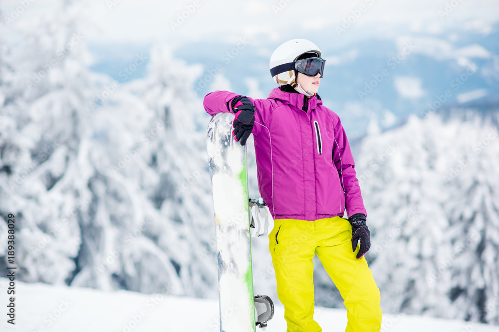一位年轻的单板滑雪女子站在户外雪山上的肖像