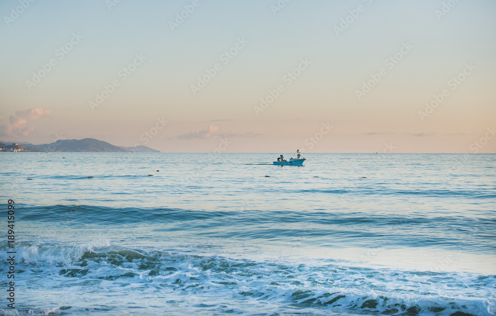 平静的傍晚地中海和日落时的小渔民船，柔和的颜色