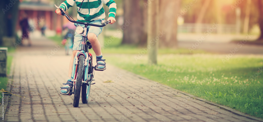 夏天孩子在柏油路上骑自行车。公园里的自行车