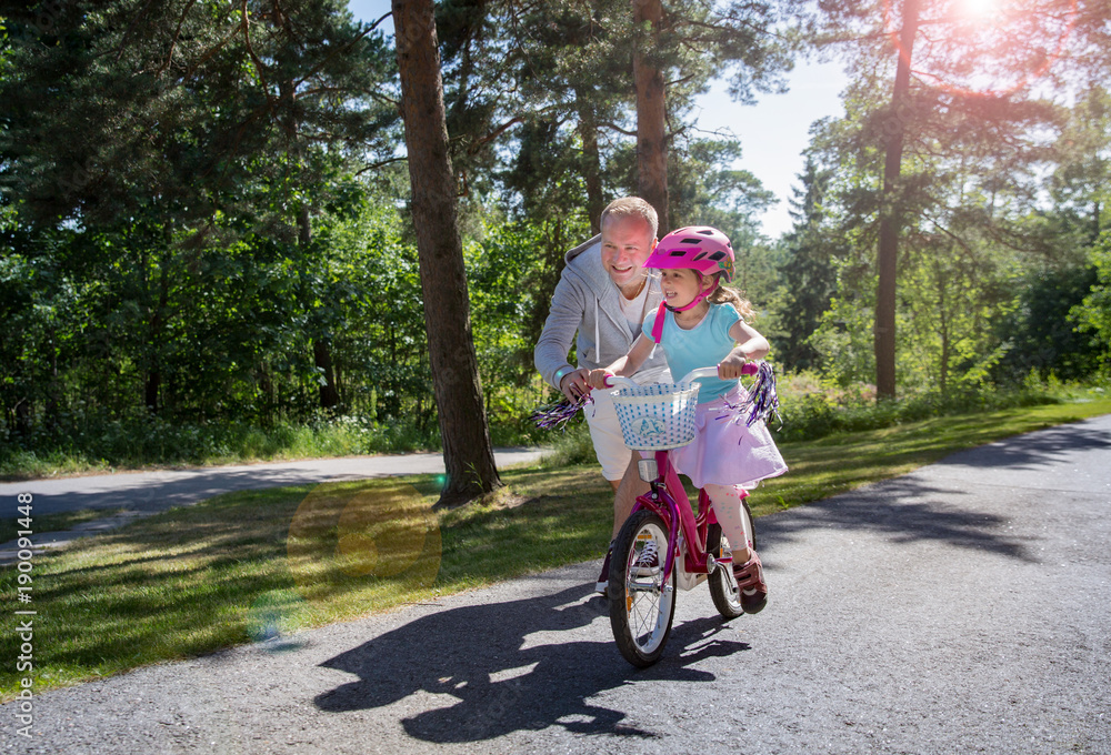 父亲教女儿骑自行车。快乐的孩子学习骑自行车。家人花时间t