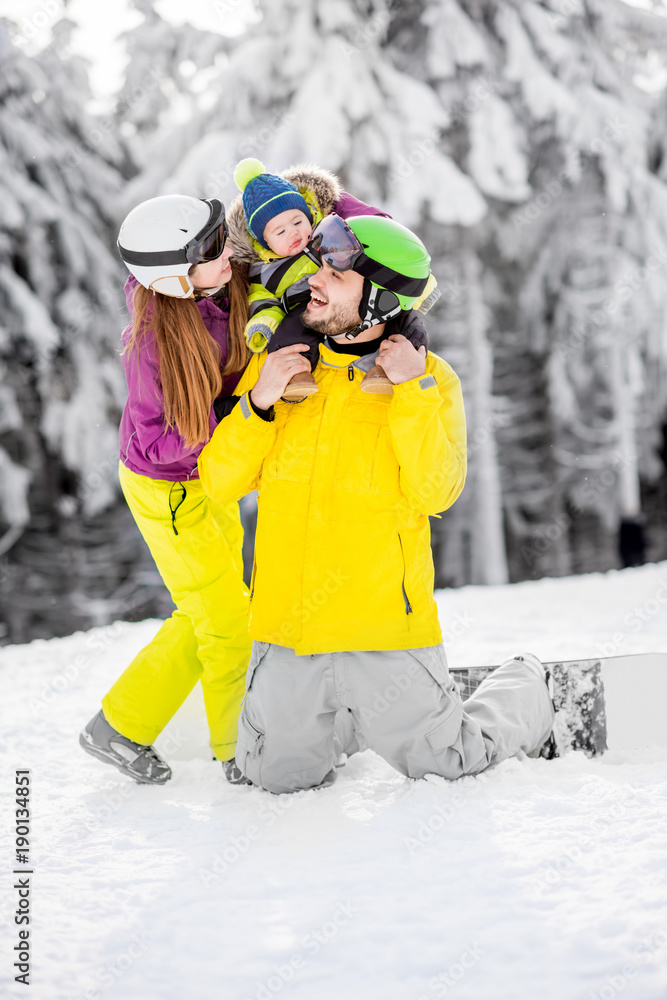 寒假期间，一个幸福的家庭在美丽的山上与男婴玩耍的肖像