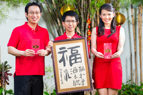 Couple celebrate Chinese new year with traditional money gift and calligraphy, wearing red