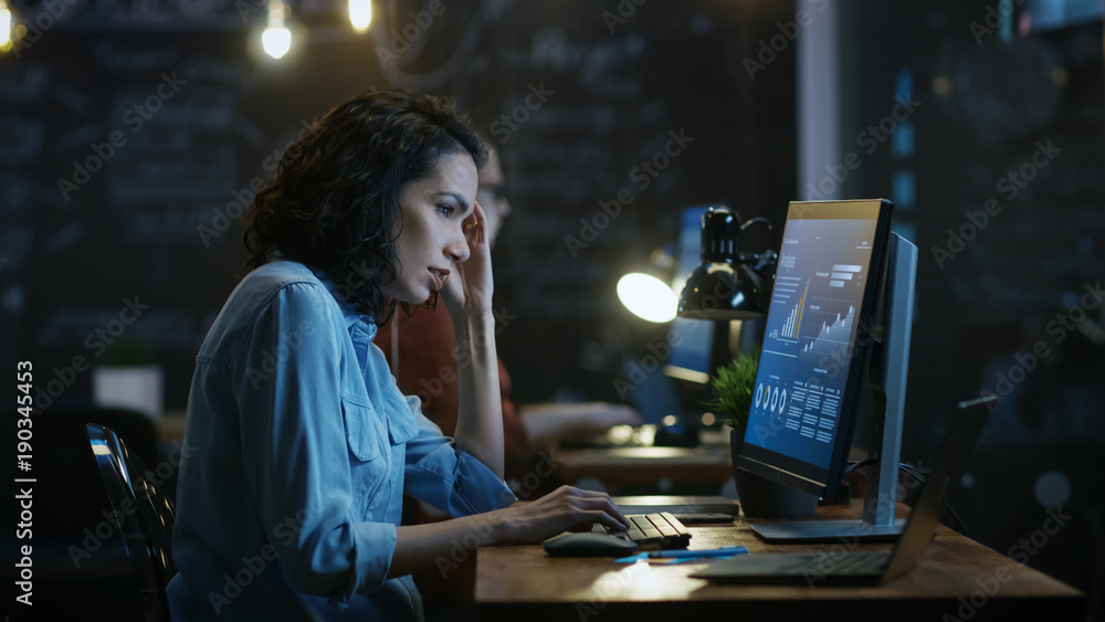 压力重重、工作过度的女金融家在个人电脑上工作时双手抱头。