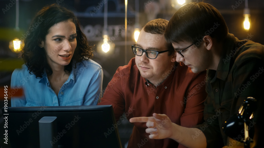 三名办公室员工讨论正在进行的项目，他们指着个人电脑屏幕