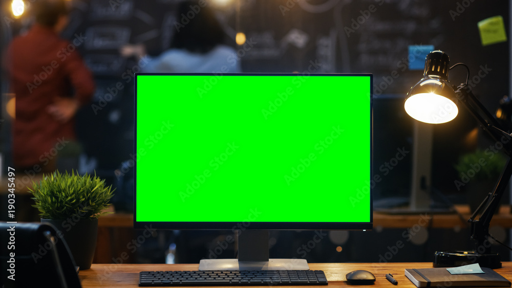 办公桌上的带实体绿屏显示器的个人电脑，在后台