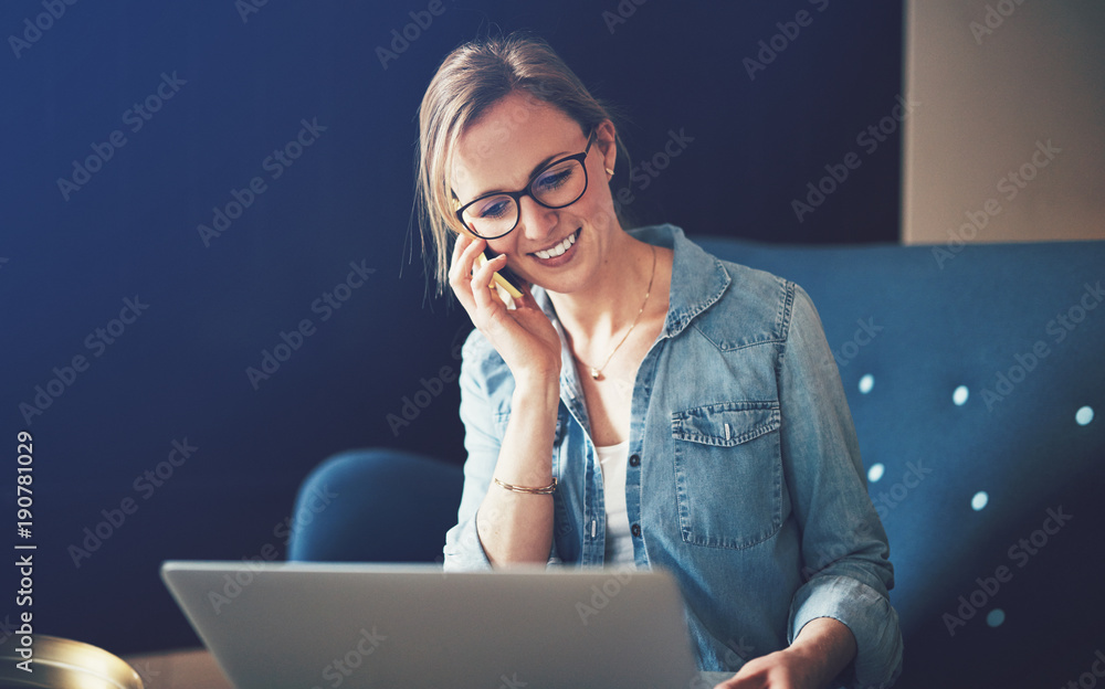 微笑的女商人用手机和笔记本电脑聊天
