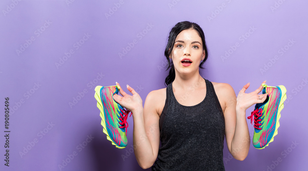 Happy young woman holding shoes on a solid background