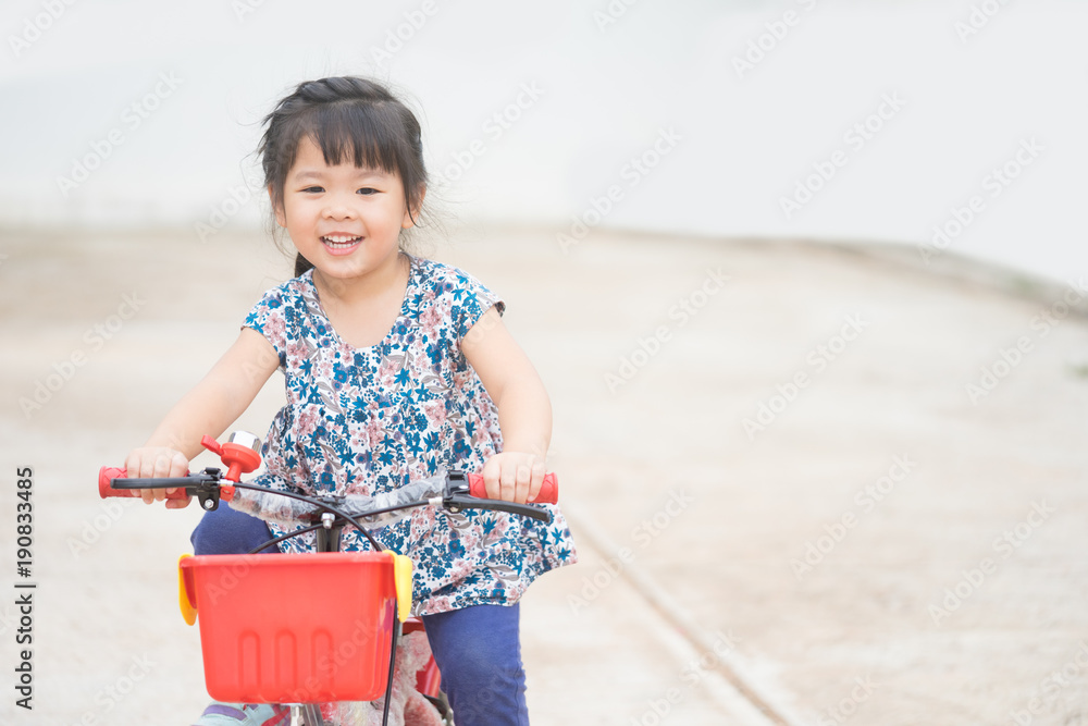 快乐的亚洲小女孩，清晨在家门口骑着自行车。