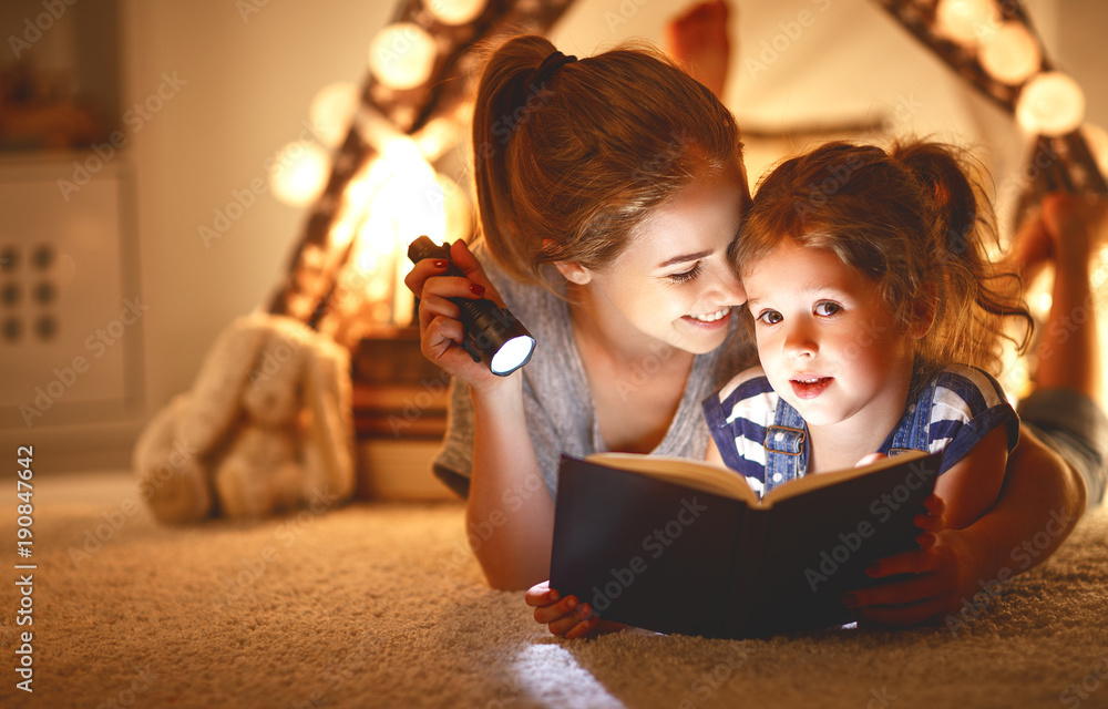 母亲和孩子的女儿在睡觉前拿着一本书和一个手电筒。