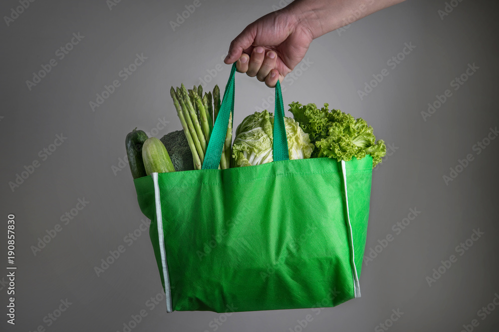 近距离手持混合有机绿色蔬菜的绿色食品袋，健康有机谷物