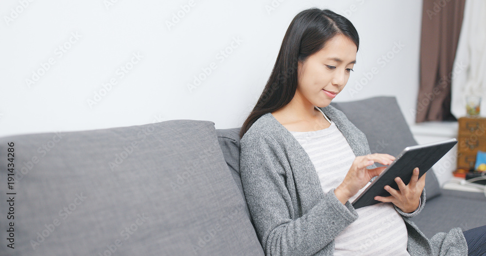 Pregnant woman using tablet computer at home