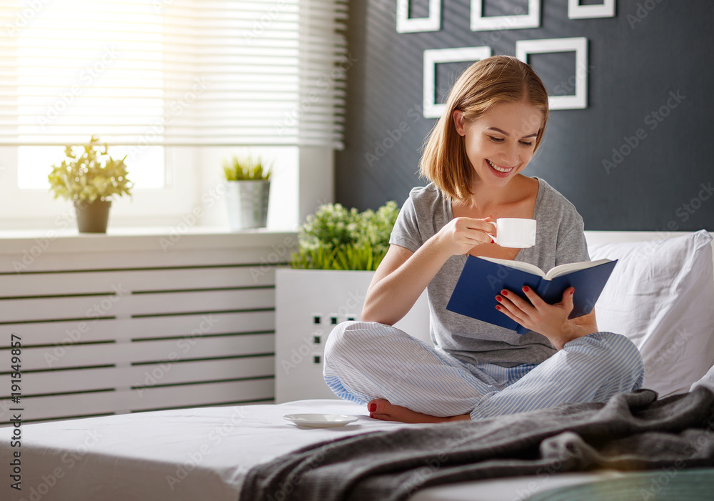 快乐的年轻女人在床上看书喝咖啡