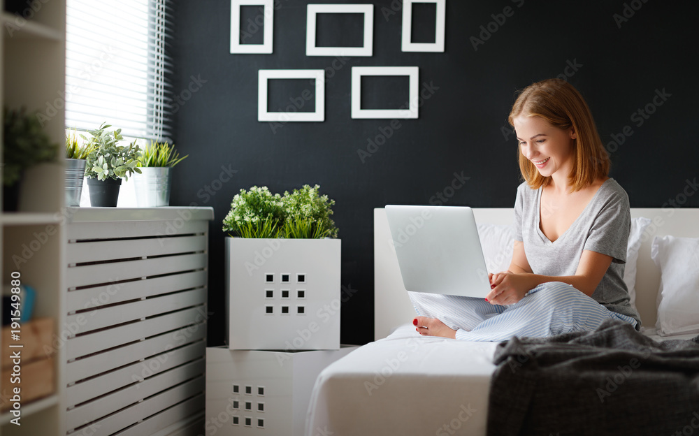年轻漂亮的女人，早上在床上拿着笔记本电脑和一杯咖啡
