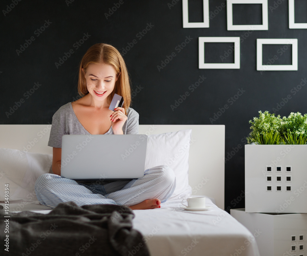 年轻漂亮的女人，早上在床上拿着笔记本电脑和一杯咖啡。