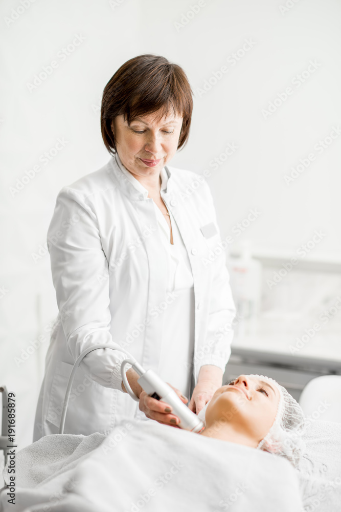 Senior woman cosmetologist making facial procedure to a young client in a luxury medical resort offi