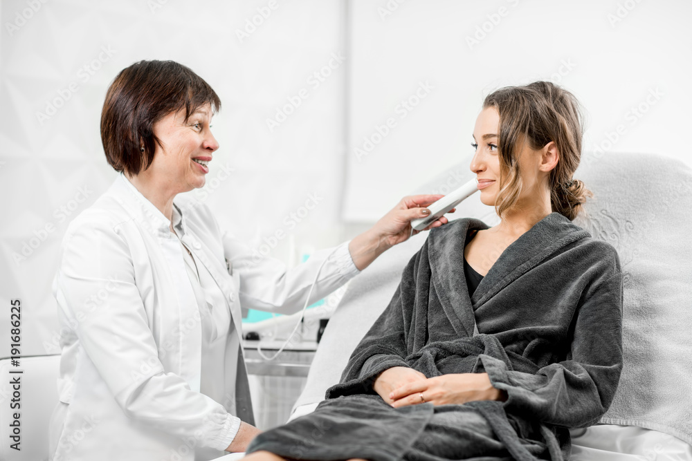 资深女性美容师在医疗中心用专业工具测量皮肤干燥度