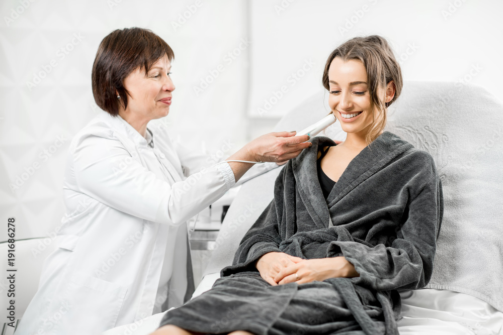 资深女性美容师在医疗中心用专业工具测量皮肤干燥度